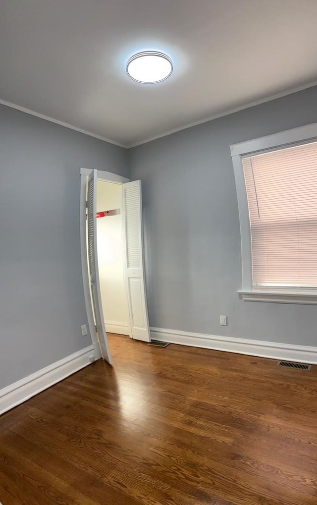 unfurnished room with dark hardwood / wood-style flooring and ornamental molding