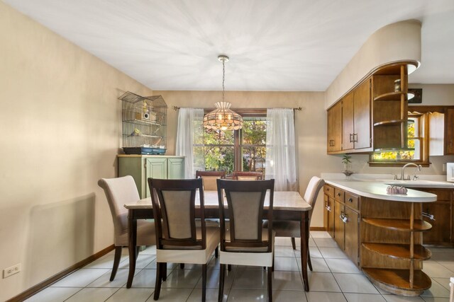 dining space featuring light tile patterned floors, a notable chandelier, and sink