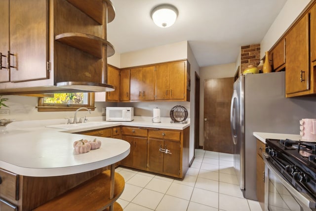 kitchen featuring stainless steel range with gas stovetop, light tile patterned flooring, sink, and kitchen peninsula