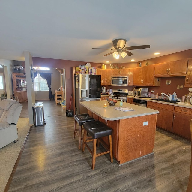 kitchen featuring a kitchen island, appliances with stainless steel finishes, sink, a kitchen breakfast bar, and dark hardwood / wood-style flooring