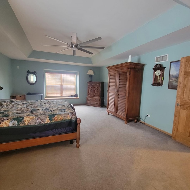 carpeted bedroom featuring ceiling fan and a raised ceiling