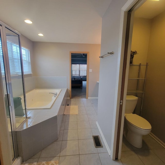 bathroom with tile patterned flooring, a relaxing tiled tub, and toilet