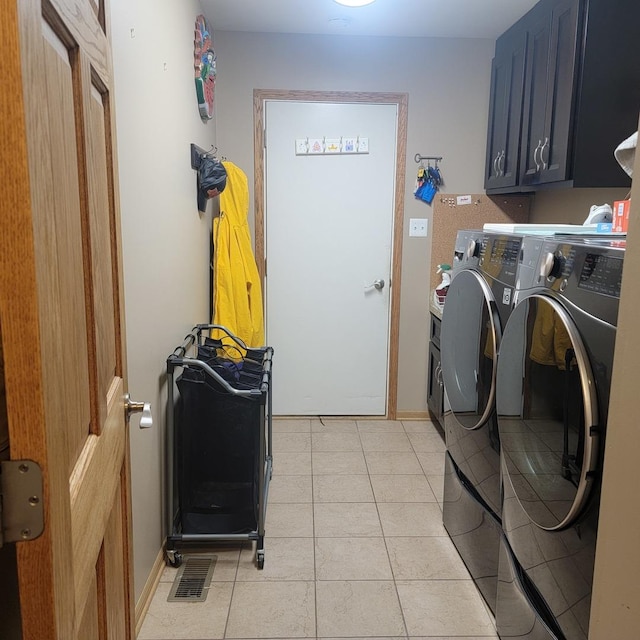 laundry room featuring light tile patterned floors, cabinets, and washing machine and clothes dryer