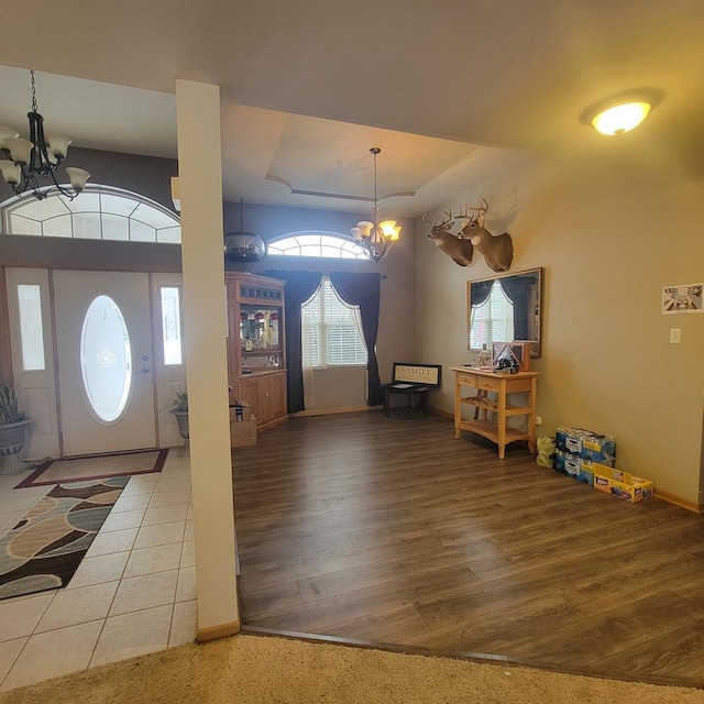 foyer featuring an inviting chandelier, a raised ceiling, and hardwood / wood-style flooring