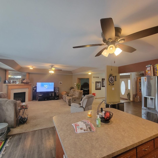 dining area with dark wood-type flooring, a tile fireplace, and ceiling fan