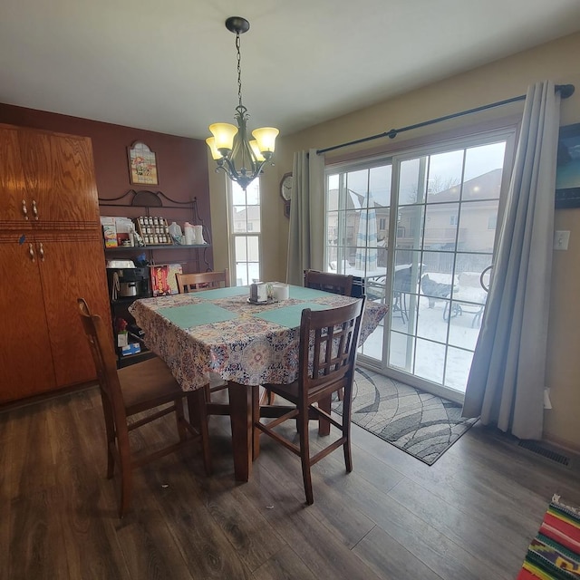 dining space with dark hardwood / wood-style floors and a chandelier