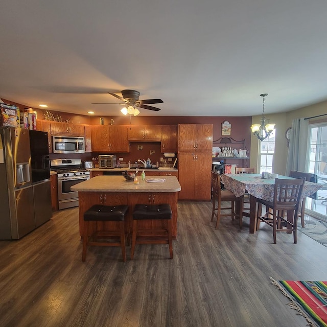 kitchen with hanging light fixtures, a center island with sink, dark hardwood / wood-style floors, and appliances with stainless steel finishes