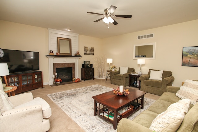 carpeted living room featuring a tile fireplace and ceiling fan