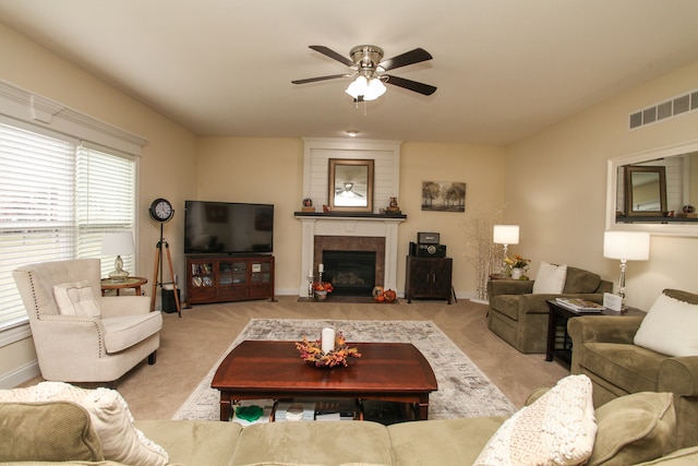 carpeted living room with a tile fireplace and ceiling fan