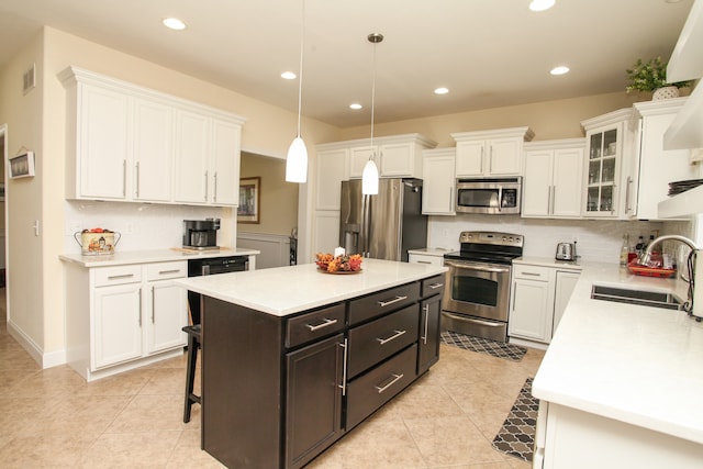 kitchen featuring a kitchen island, stainless steel appliances, sink, pendant lighting, and white cabinets