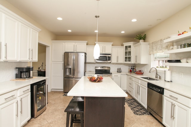 kitchen featuring a kitchen island, pendant lighting, white cabinetry, beverage cooler, and appliances with stainless steel finishes