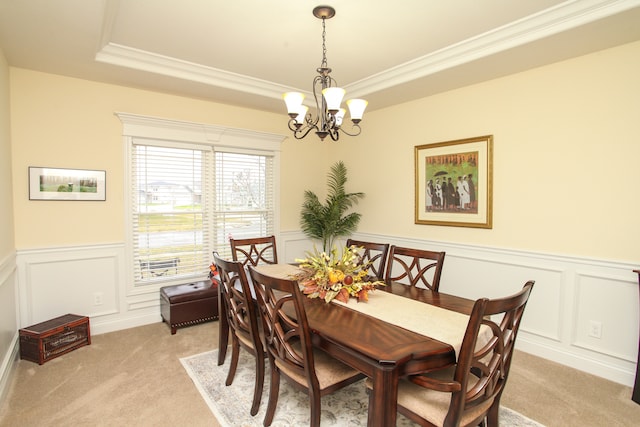 dining area featuring ornamental molding, light carpet, a tray ceiling, and an inviting chandelier