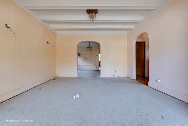 carpeted empty room featuring beam ceiling