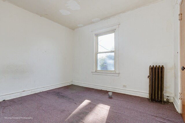 carpeted spare room featuring radiator heating unit