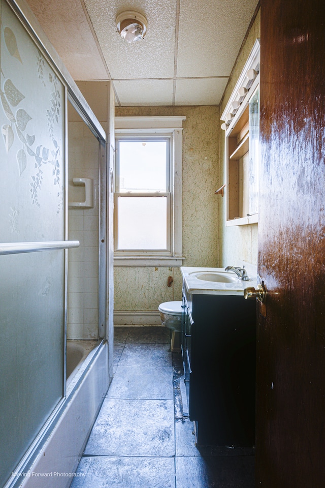 full bathroom featuring vanity, toilet, enclosed tub / shower combo, and a paneled ceiling