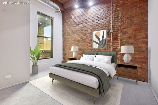 bedroom with light carpet and brick wall