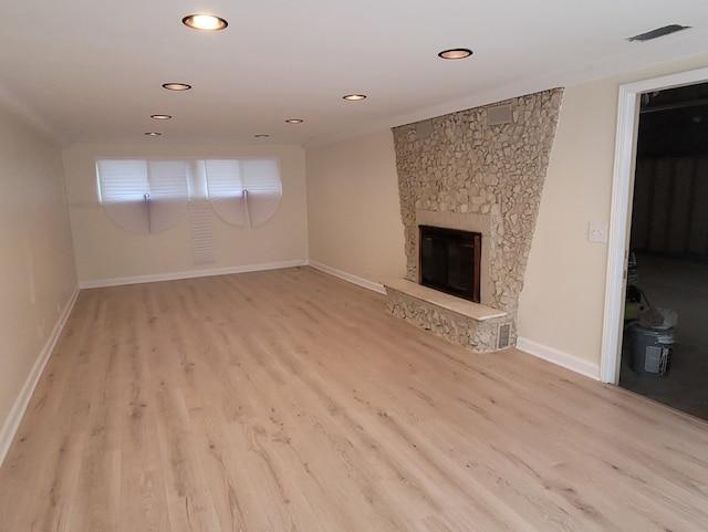 unfurnished living room featuring a stone fireplace and light hardwood / wood-style floors