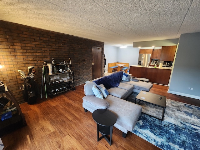 living room featuring hardwood / wood-style floors, a textured ceiling, and brick wall