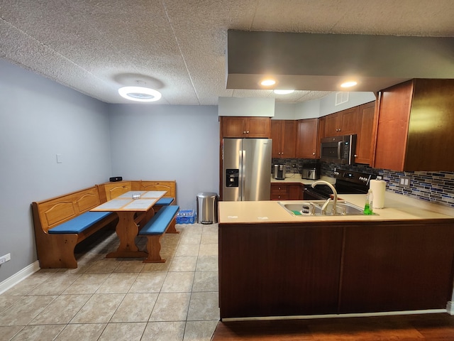 kitchen with kitchen peninsula, appliances with stainless steel finishes, decorative backsplash, and light tile patterned floors