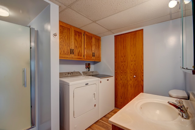 laundry room featuring washing machine and dryer, sink, and light hardwood / wood-style floors