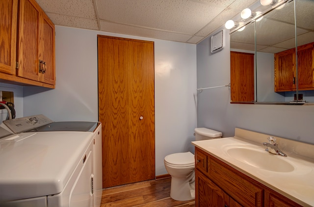 bathroom with separate washer and dryer, toilet, a paneled ceiling, vanity, and hardwood / wood-style flooring