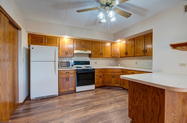 kitchen featuring kitchen peninsula, tasteful backsplash, a textured ceiling, white appliances, and dark hardwood / wood-style floors