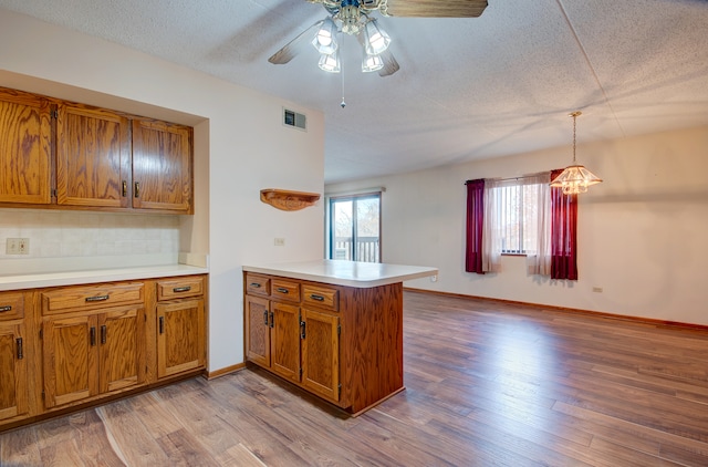 kitchen with kitchen peninsula, a textured ceiling, light wood-type flooring, and hanging light fixtures