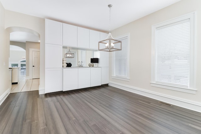 kitchen with white cabinets, pendant lighting, a notable chandelier, and hardwood / wood-style flooring