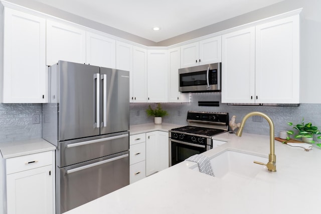 kitchen with appliances with stainless steel finishes, white cabinetry, sink, and decorative backsplash