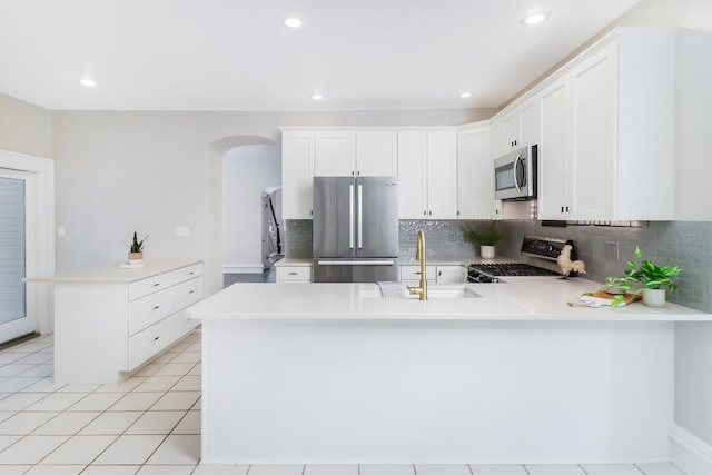 kitchen featuring stainless steel appliances, light tile patterned floors, decorative backsplash, sink, and white cabinetry