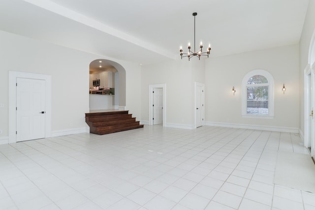 tiled spare room featuring an inviting chandelier