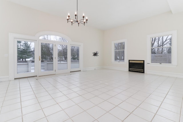 unfurnished living room with a healthy amount of sunlight, light tile patterned floors, and a chandelier