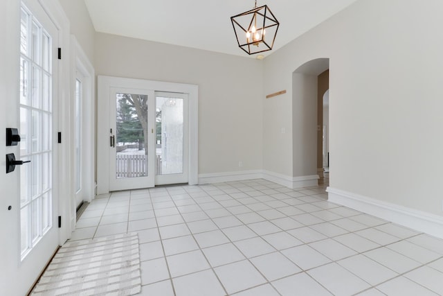 tiled empty room with a notable chandelier