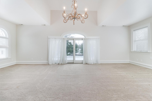 unfurnished room featuring light colored carpet and a notable chandelier