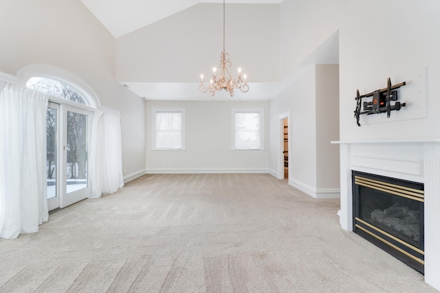 unfurnished living room with high vaulted ceiling, a notable chandelier, and light colored carpet