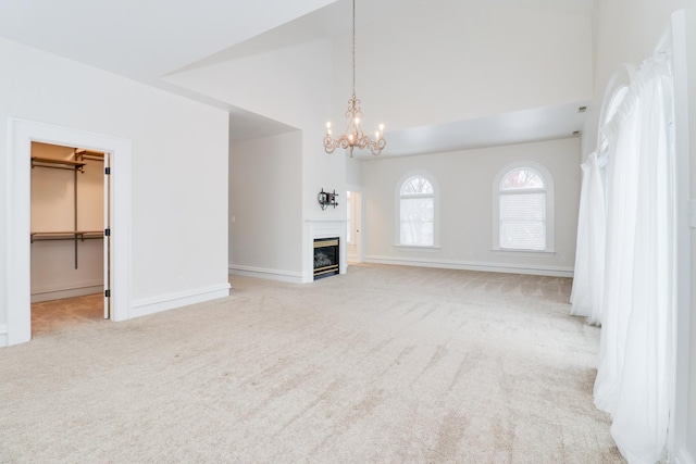 unfurnished living room with lofted ceiling, a chandelier, and light carpet