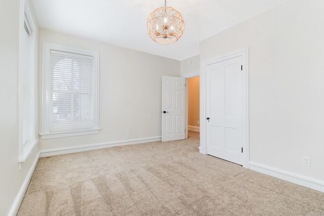 carpeted empty room with an inviting chandelier