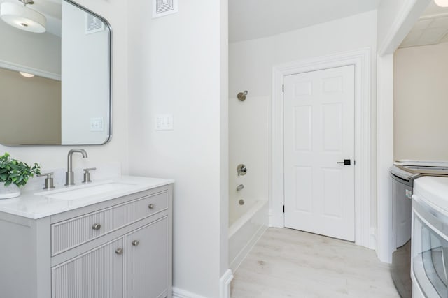 full bathroom featuring toilet, vanity, washing machine and clothes dryer, and washtub / shower combination