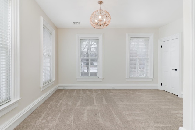 carpeted spare room with a notable chandelier