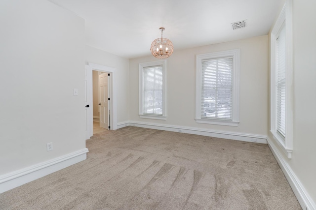 carpeted empty room with a chandelier