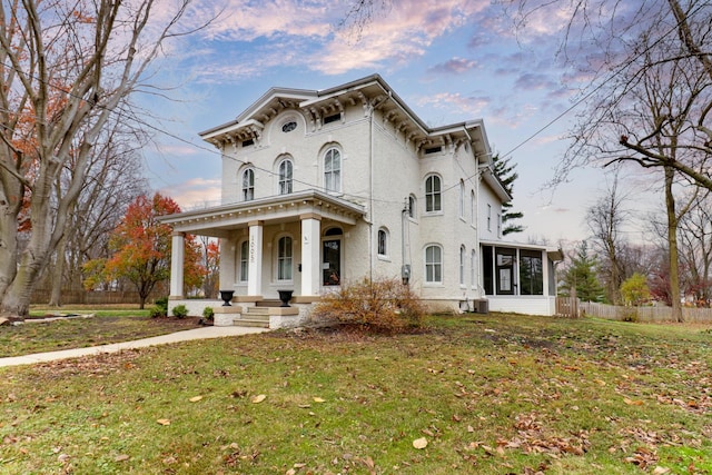 italianate-style house with a porch, a yard, and a sunroom