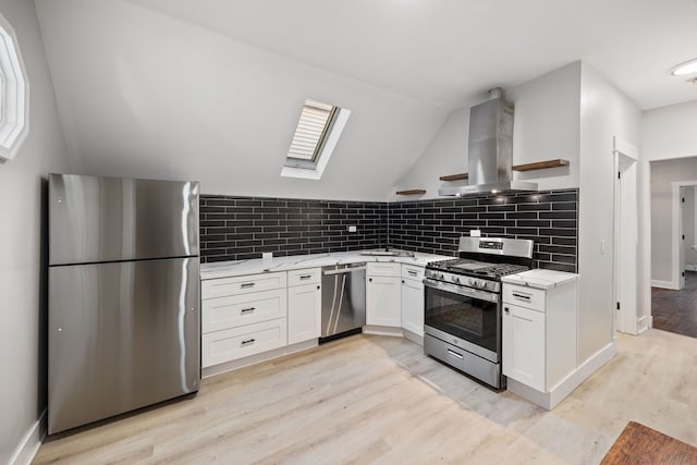 kitchen featuring appliances with stainless steel finishes, light wood-type flooring, white cabinetry, and wall chimney range hood