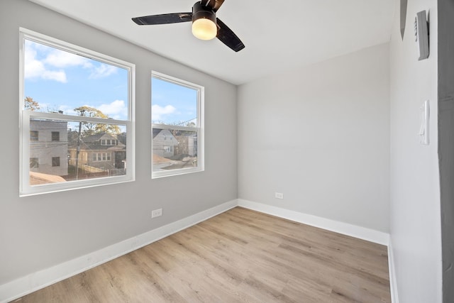 spare room with light wood-type flooring, a wealth of natural light, and ceiling fan