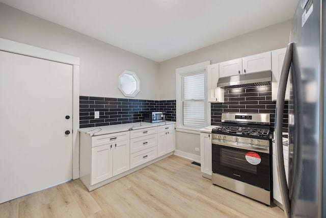 kitchen featuring light stone countertops, appliances with stainless steel finishes, light wood-type flooring, tasteful backsplash, and white cabinetry