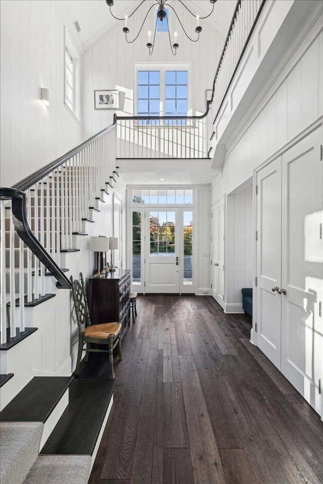 foyer with a chandelier, high vaulted ceiling, dark hardwood / wood-style floors, and a healthy amount of sunlight