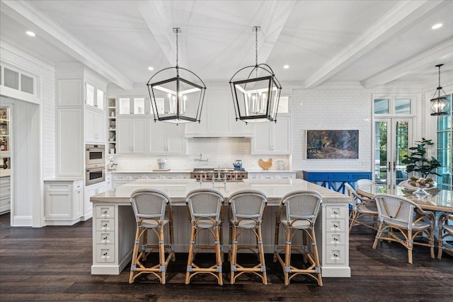 kitchen with hanging light fixtures, a center island with sink, and white cabinets