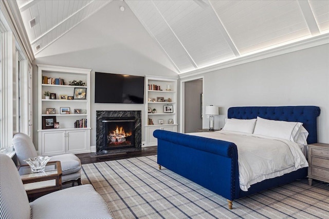 bedroom featuring a premium fireplace, vaulted ceiling with beams, and hardwood / wood-style floors