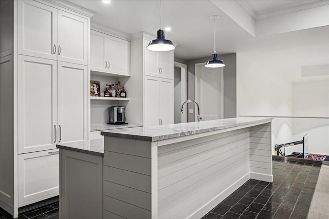 kitchen featuring white cabinetry, an island with sink, light stone counters, and decorative light fixtures