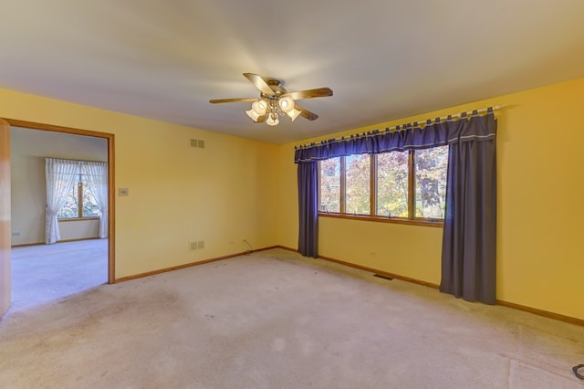 empty room with light carpet, a healthy amount of sunlight, and ceiling fan