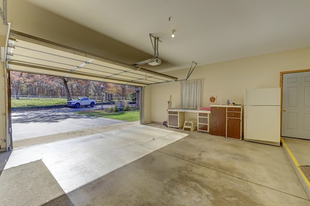 garage with a garage door opener and white refrigerator